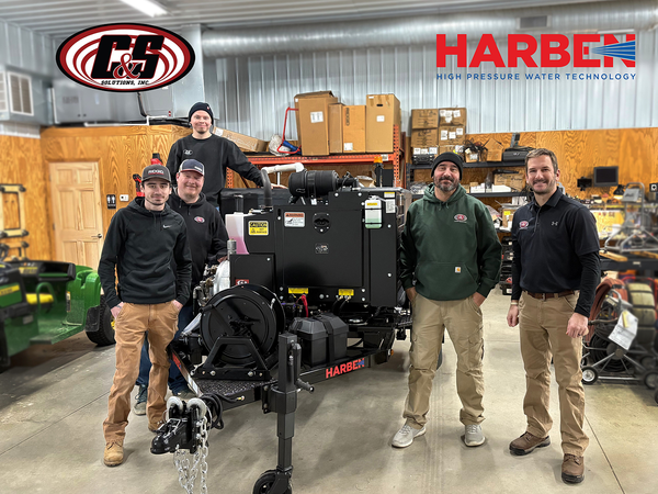 C&S Solutions team standing together in a warehouse with a Harben high-pressure water jetting unit.