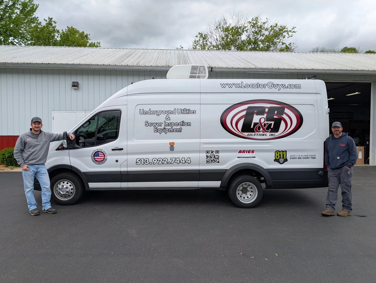Two staff members standing beside a Locator Guys branded service van for underground utility and sewer inspection equipment.