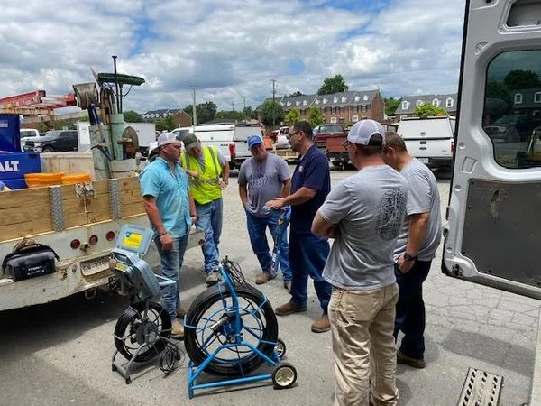 Group of technicians gathered around a portable pipeline inspection reel system during outdoor field equipment training.