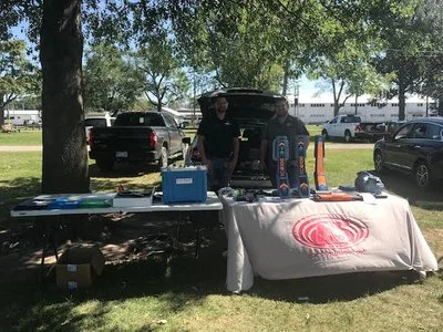 Locating equipment and tools displayed on a table under a tree at an outdoor event.
