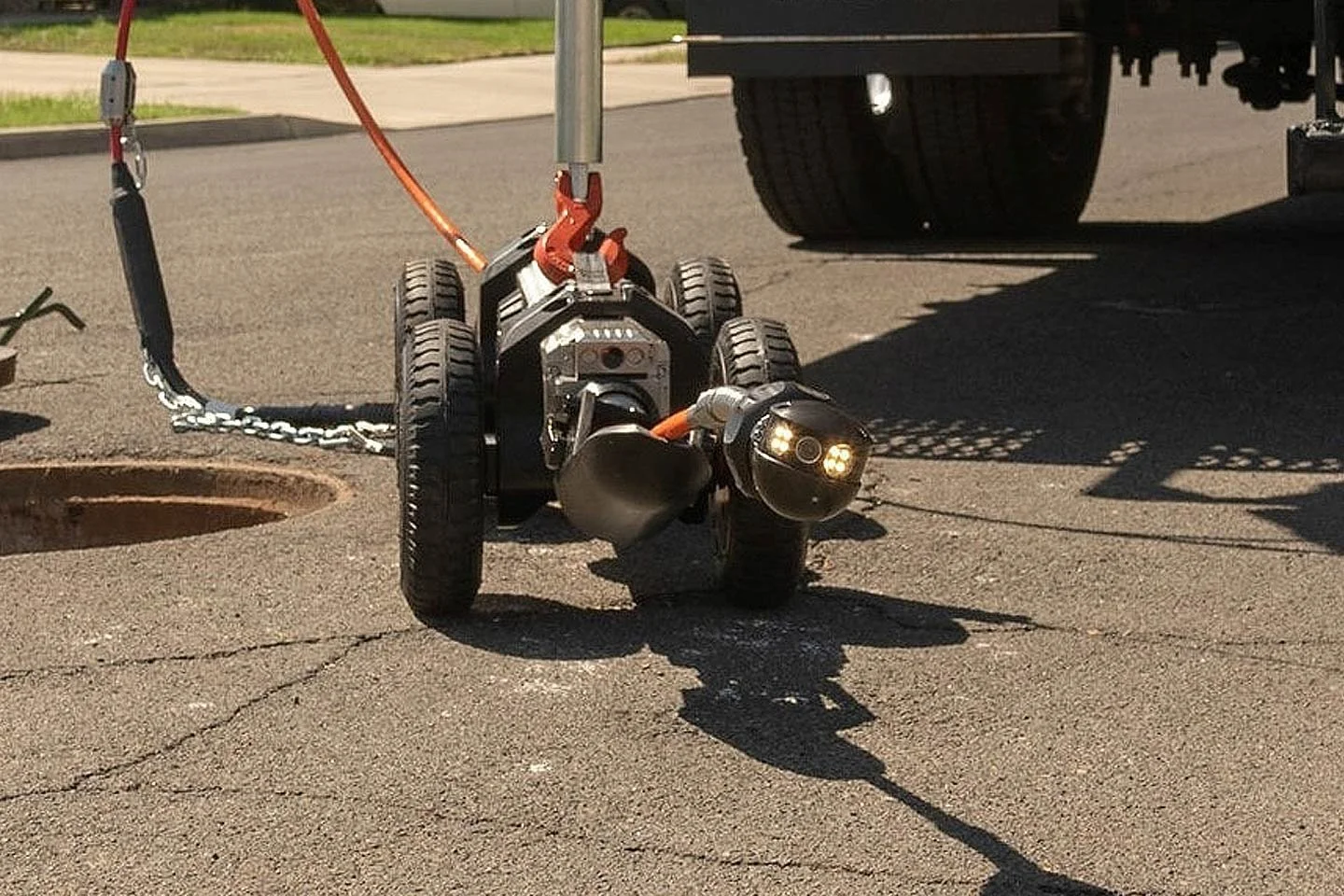 LETS 6.0 lateral inspection crawler at a manhole with its camera lights illuminated.