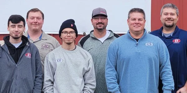 Group photo of the C&S Solutions team wearing branded company apparel.