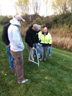 Crew members gathered around utility locating equipment on a grass field.