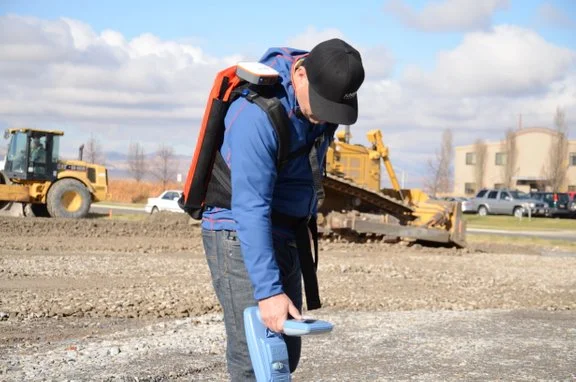 Technician using a Radiodetection RD8200G GPS-integrated utility locator at a construction site.