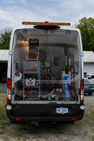 Rear exterior of the sewer inspection van with back doors open, revealing mounted equipment inside.