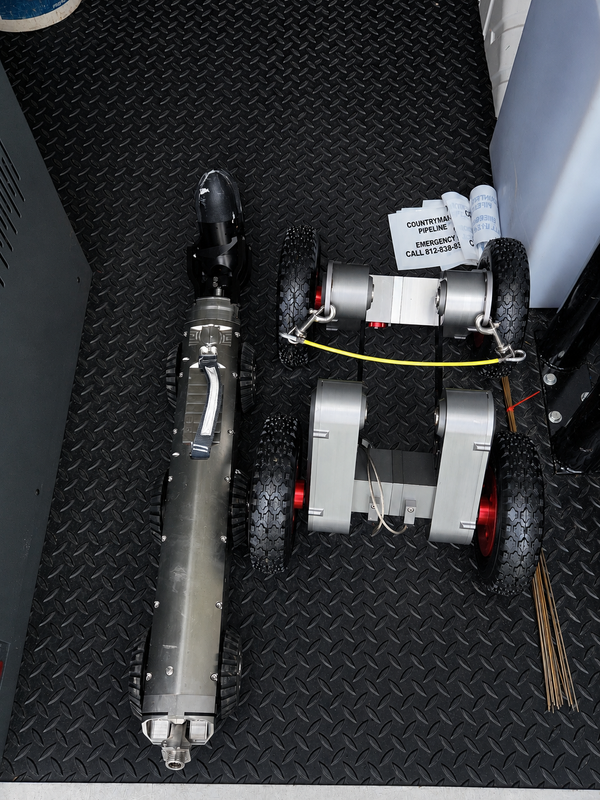 Mainline sewer inspection crawler and camera stored on the diamond plate floor of an inspection van.