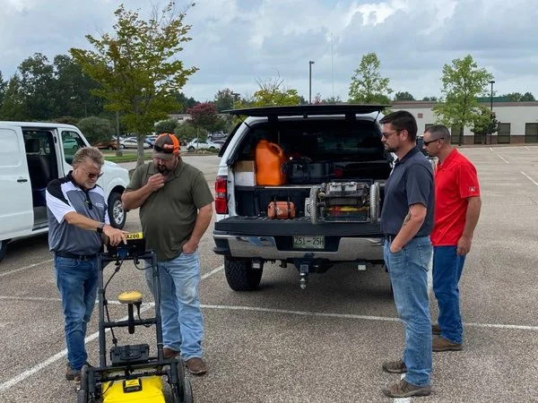 Group of technicians examining a Radiodetection LMX200 GPR cart during an outdoor equipment demonstration.