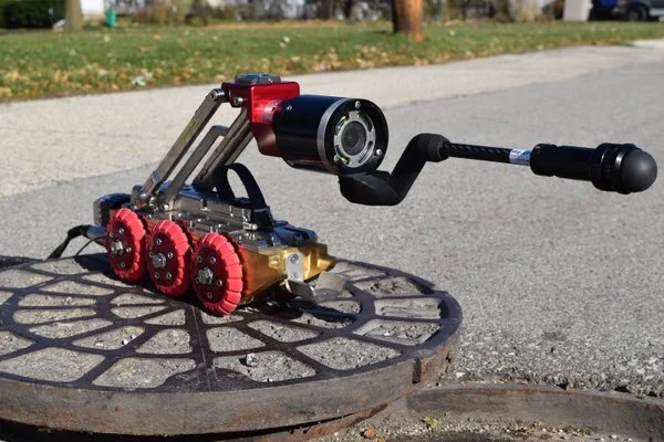 Aries pipeline inspection crawler with articulating camera positioned on a manhole cover.