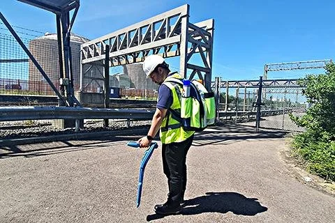Technician wearing a Radiodetection backpack while using a locator on a bridge job site.