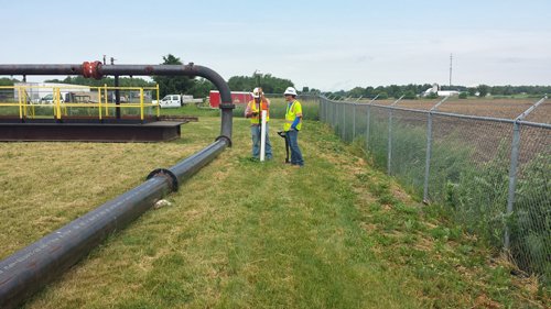 Large-diameter pipe laid across a grass field during a directional drilling equipment demonstration.