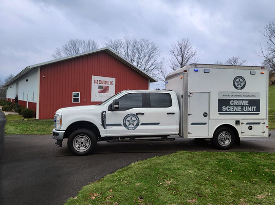 Locator Guys branded service truck with equipment trailer parked outside a barn.