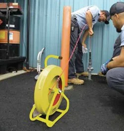 Technicians using a Jameson Live Gas/Water Rodder with fiberglass rod at a job site.