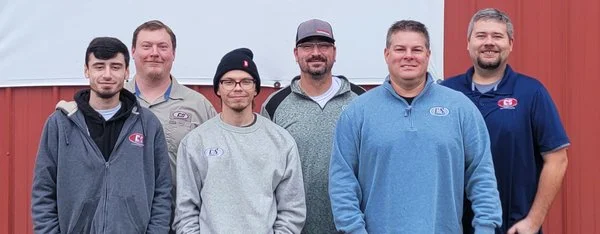 Group photo of the C&S Solutions team wearing branded company apparel.