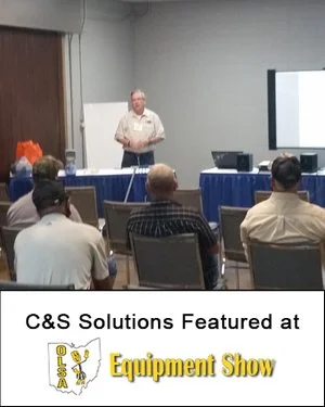 C&S Solutions training session held at an equipment show, with attendees seated in a classroom setting.