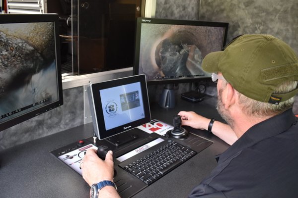 Operator monitoring multiple screens while controlling the Aries LETS Sidewinder lateral inspection system from a laptop.