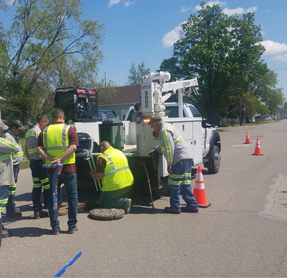 Crew members in high-visibility vests training on an Aries P550 pipe inspection crawler system in a residential street.