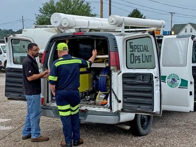 Two technicians loading pipeline inspection equipment into a "Special Ops Unit" service van.