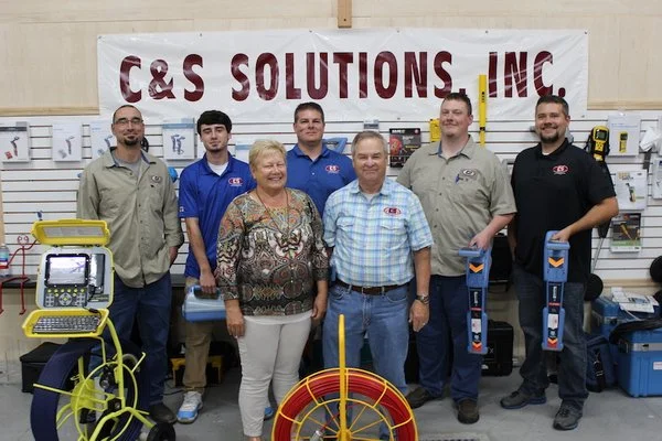 C&S Solutions, Inc. staff team group photo standing with utility locating and pipe inspection equipment.