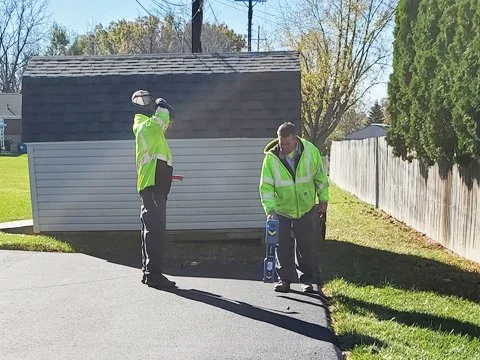 Technicians training on a Radiodetection RD8100PDL receiver and TX10 transmitter beside a building.