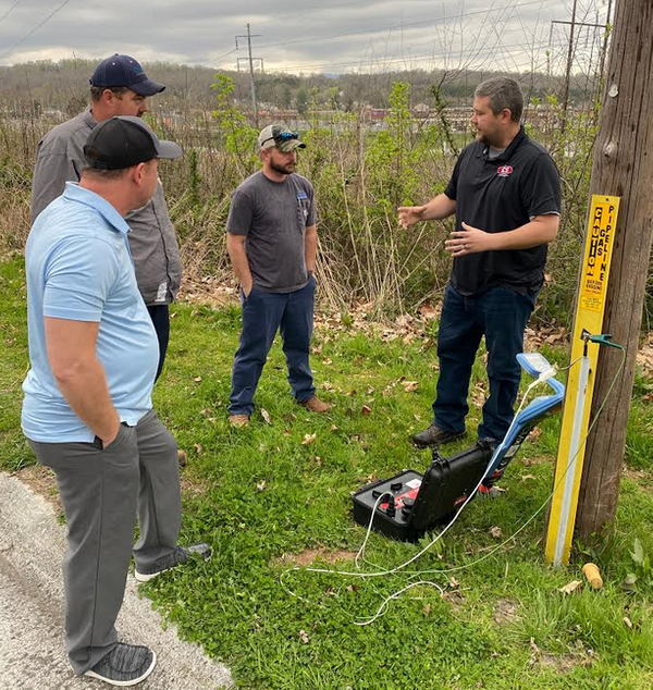 Group of technicians gathered near a utility pole during hands-on underground utility locating equipment training.