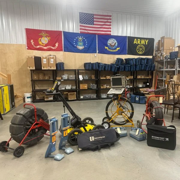 Showroom display of underground utility locating and pipe inspection equipment including GPR cart, locators, and inspection reel.