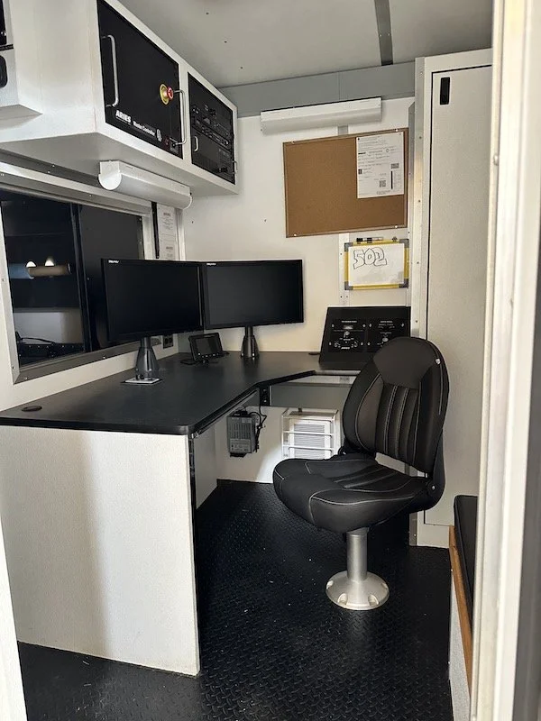 Interior operator workstation inside an Aries pipeline inspection trailer with dual monitors and control desk.