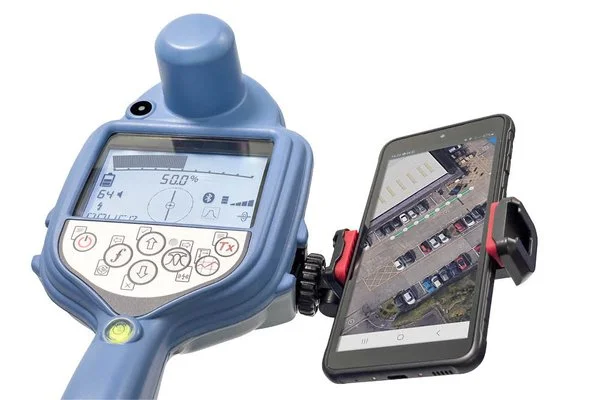 Close-up of a utility locator receiver display paired with a smartphone running a GPS mapping application.