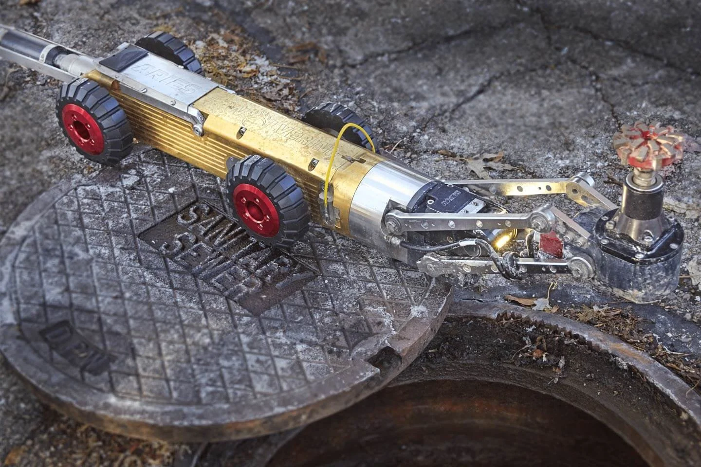Aries Wolverine robotic cutting crawler with camera positioned on a manhole cover.