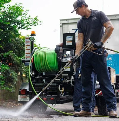 Technician operating a jetting hose reel while cleaning a sewer or drain line in the field.