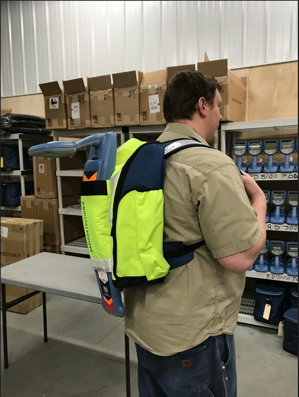 Technician wearing a Radiodetection backpack while standing in a warehouse storage area.