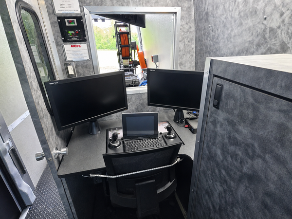 Interior control workstation inside a sewer inspection van with dual monitors and an operator seat.