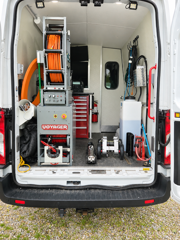 Interior of a sewer inspection van showing the Voyager cable reel, mainline crawler, and mounted equipment.