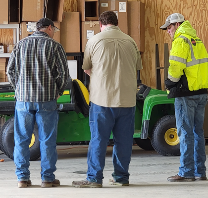 Staff and a customer standing together in the repair shop following an equipment repair.