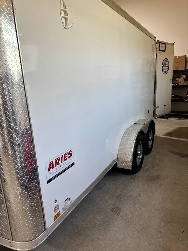 Exterior side view of an Aries Industries pipeline inspection trailer showing its dual-axle wheels and logo decal.