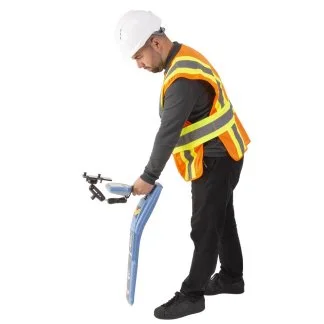 Technician in a hard hat and safety vest using a Schonstedt line locator during a field locate.