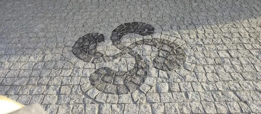 Dessine un symbole à forme de scorpion sur le pavé avec des pierres