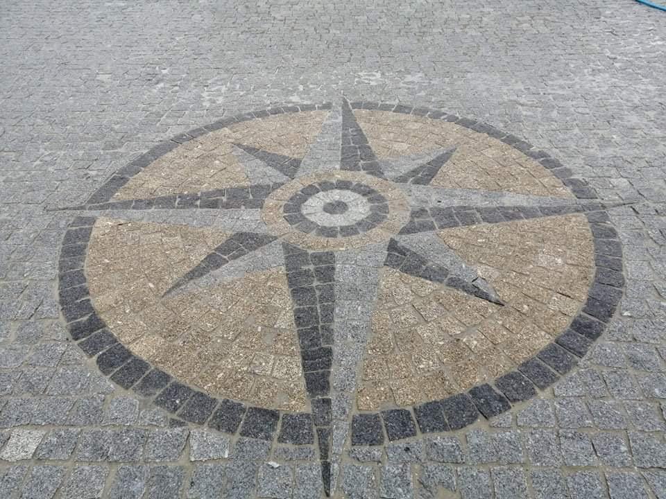Dessin de boussole murale en pierre sur un trottoir.