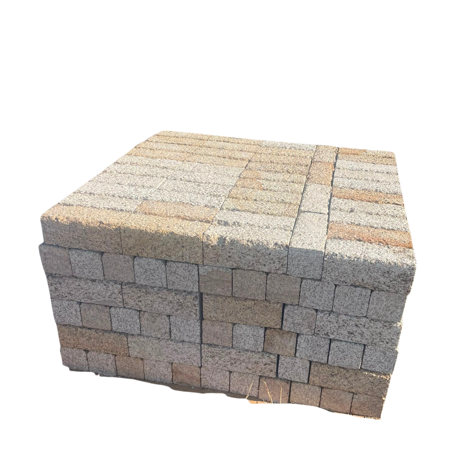 Un empilement de pavés en pierre beige, rose et gris. Le pavage occupe une grande partie de l'image, avec une ombre portée visible sur la surface.