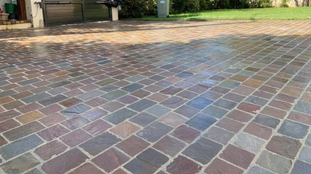 Surface pavée en pierres de différentes couleurs avec une zone délimitée par des lignes claires.