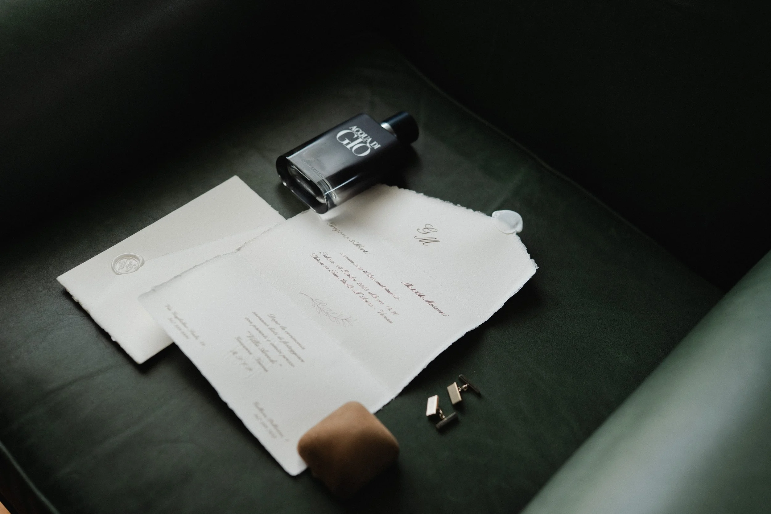 A black bottle labeled 'Aqua Di Gio' resting on a piece of torn white paper, with a black USB flash drive and a brown stick nearby.