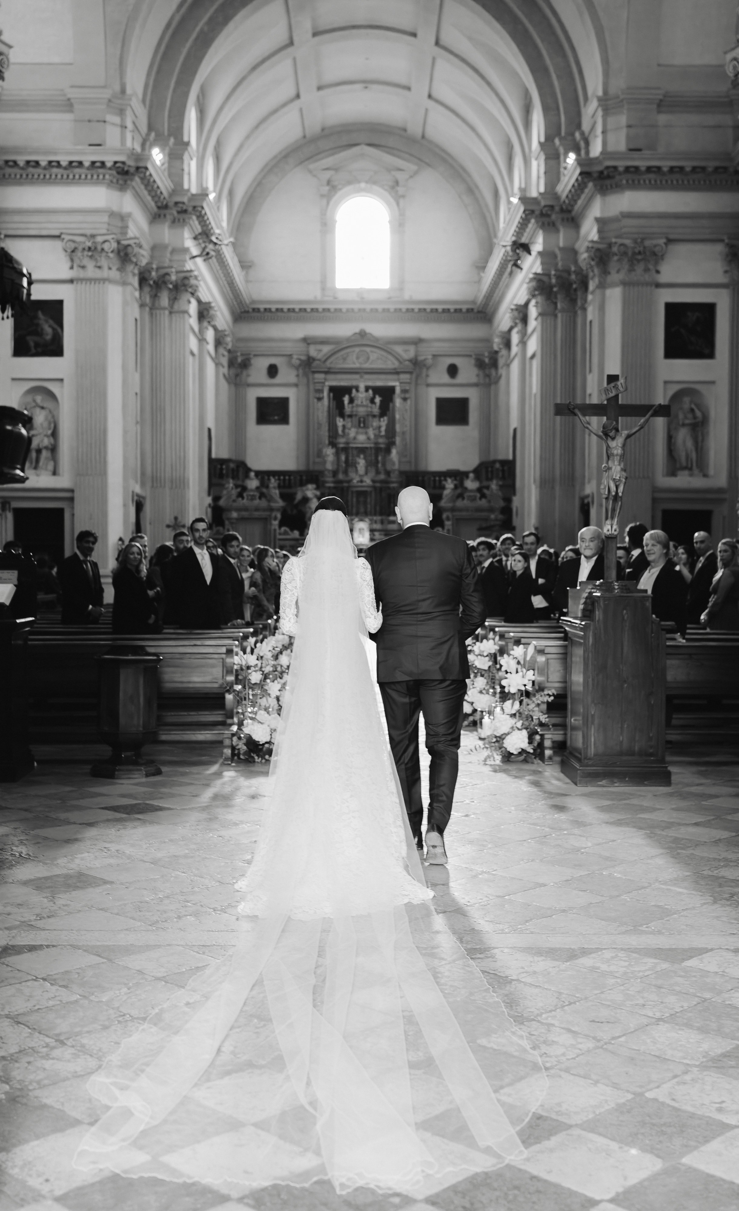 Bride and groom walking down the aisle in a church with guests watching.