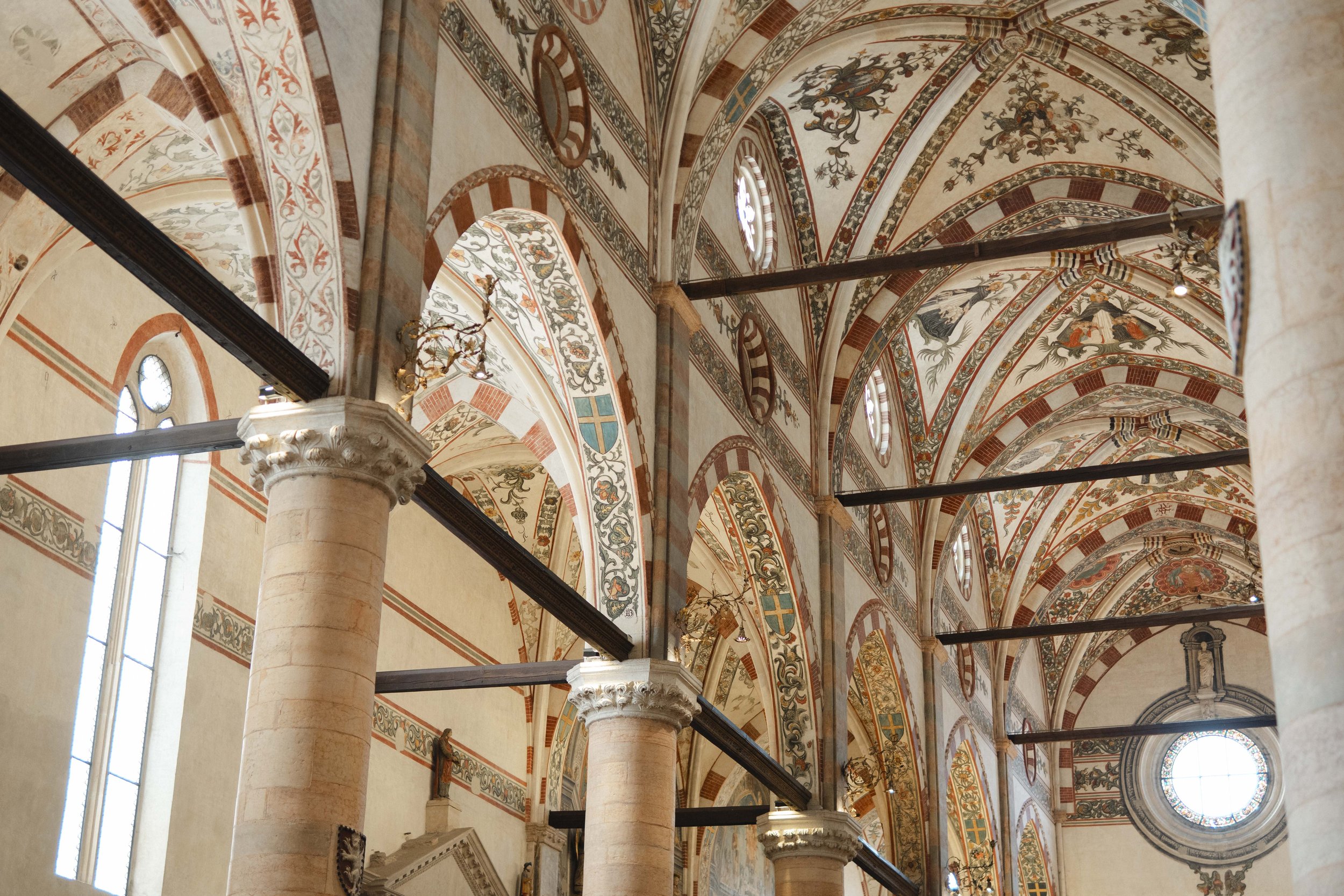 The interior of a historic church or cathedral with high, decorated arches, columns, and stained glass windows.