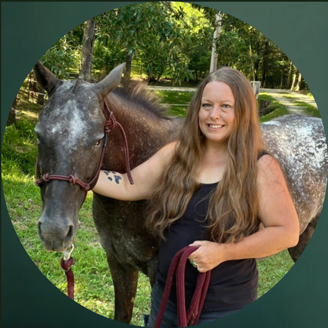 Bodyshot of smiling female farmer standing in front of horses holding a chicken..