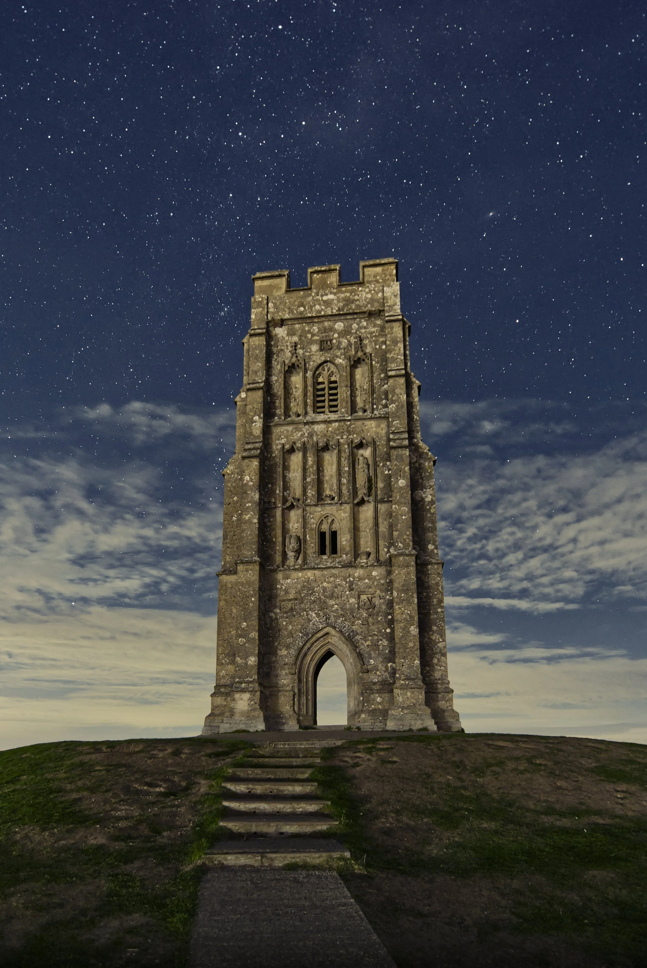 St Michael’s Tower on Glastonbury Tor beneath stars and drifting clouds, with stone steps in the foreground, Somerset