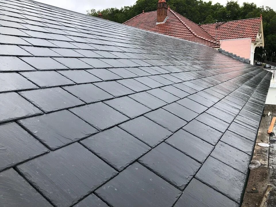 Close-up of a freshly painted black shingle roof on a house.