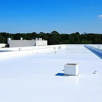 View of a white commercial building's flat roof with rooftop units and a clear blue sky.