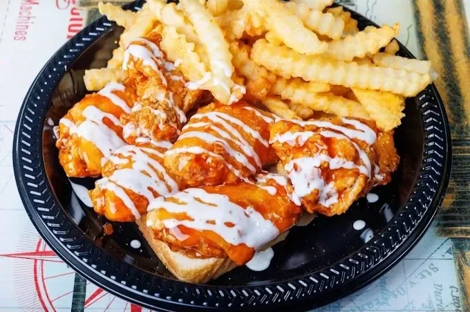  Buffalo chicken wings with white sauce and crinkle-cut fries in a black takeout container.