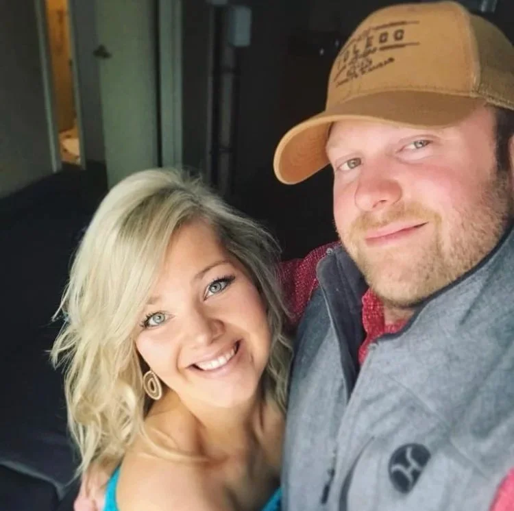 A smiling woman and a man taking a selfie together indoors.