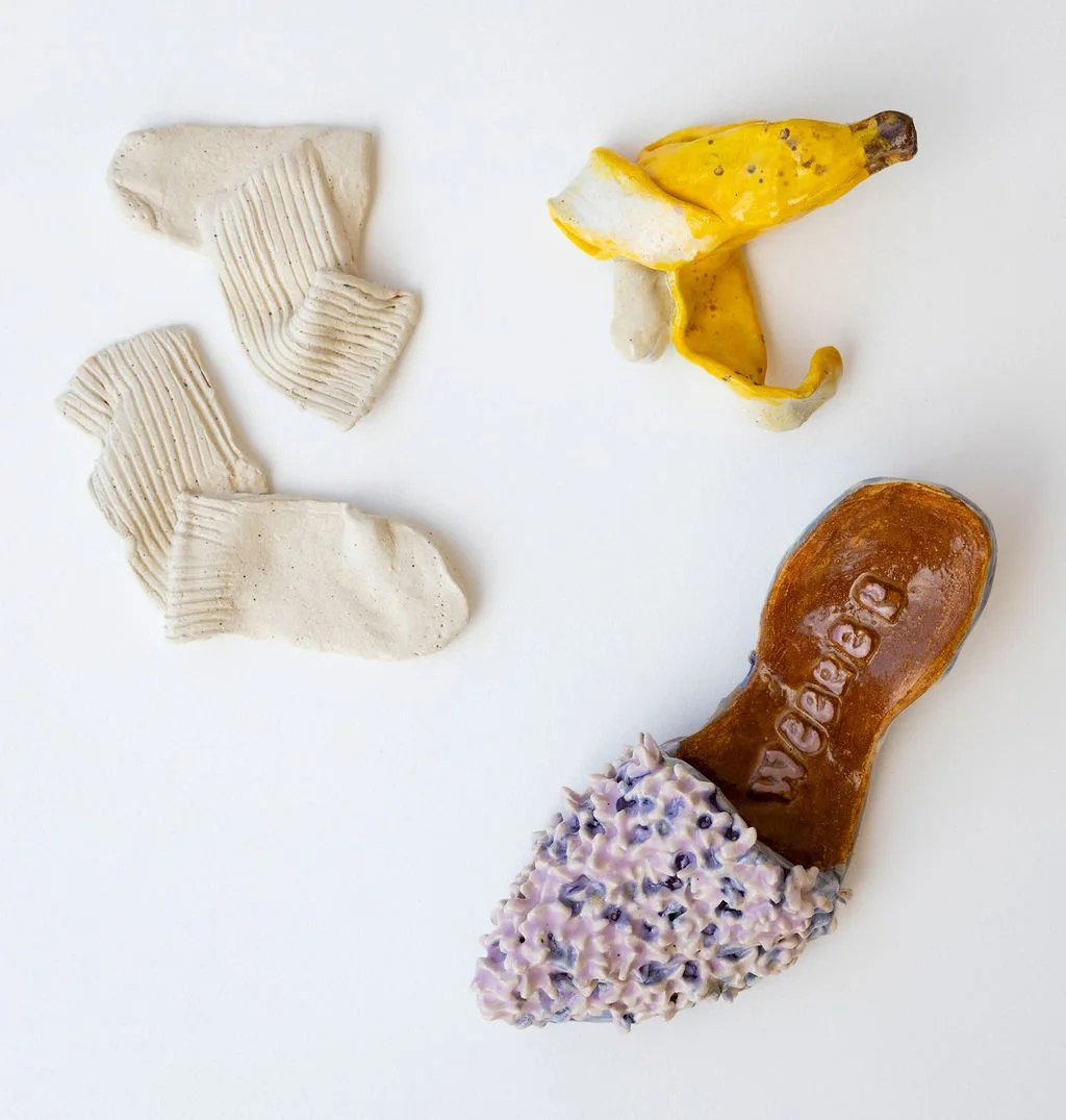 A collection of objects resembling shoes and bananas on a white background. The objects include three white, textured shoe-like shapes, a yellow banana peel, and a brown object that looks like a shoe with a purple flower-like decoration at the toe.
