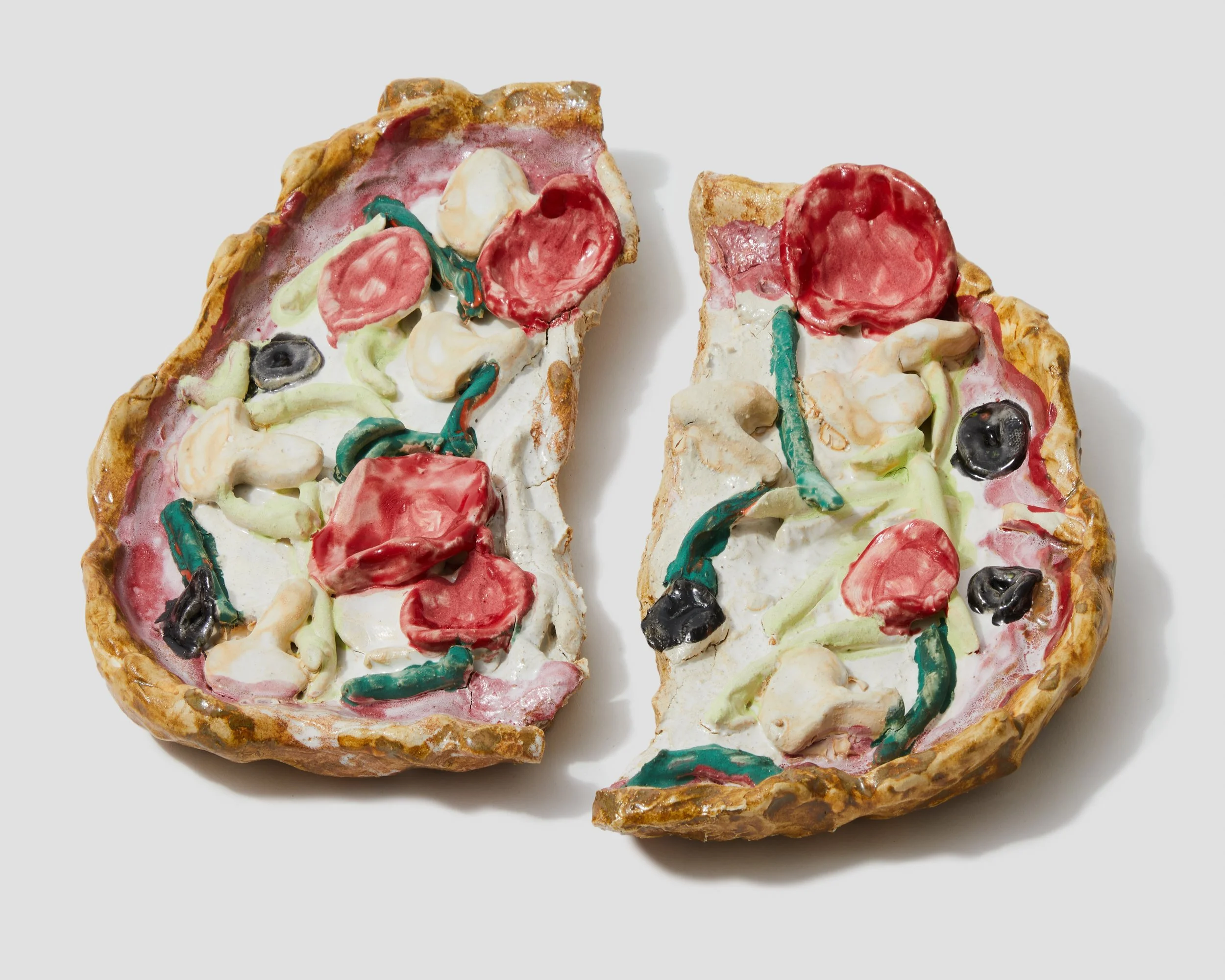 Close-up of a pizza with colorful toppings, including red and black slices, green and red stripes, on a white background.